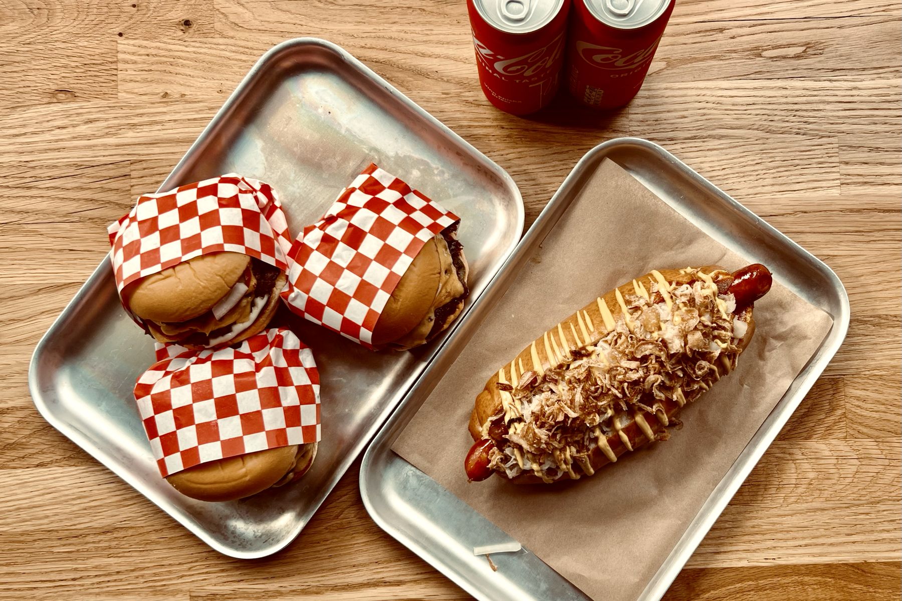 Cheeseburgare i rutigt papper och en hot dog på plåtbrickor